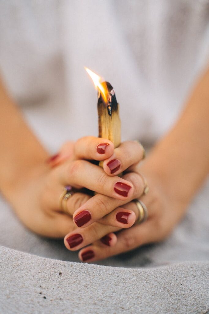 Close-up of hands holding burning Palo Santo for spiritual meditation.